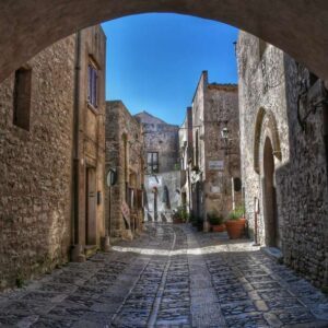 "erice una via con case di pietra sotto un arco architettonico"