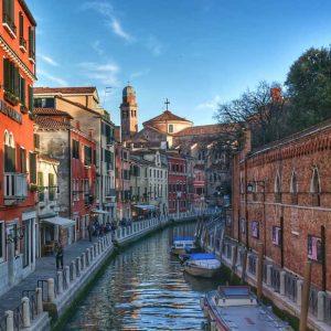 "santa croce canale con barche ormeggiate case clorate e chiesa alla fine del canale"