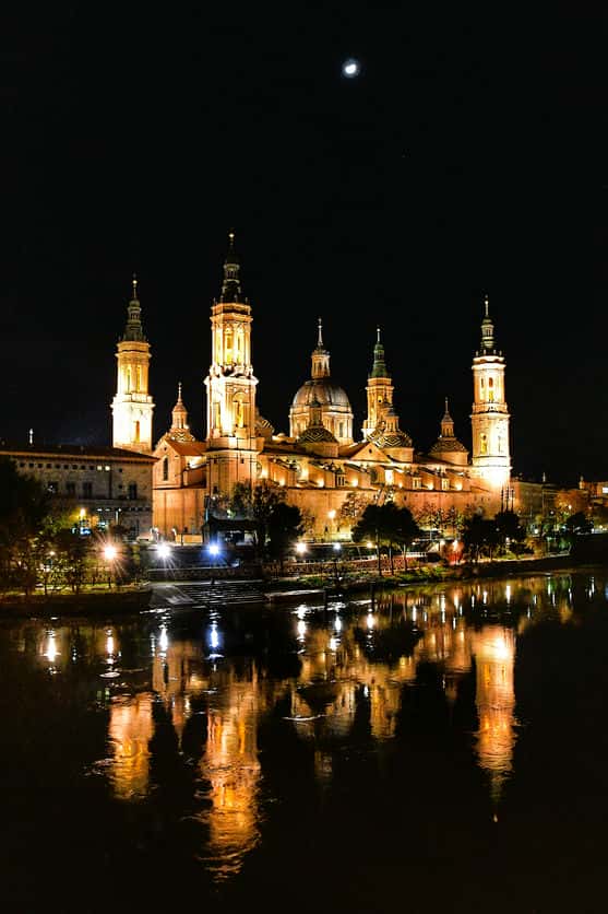 "basilica nostra signora del pilar saragozza di notte che riflette su acque del fiume calmo"