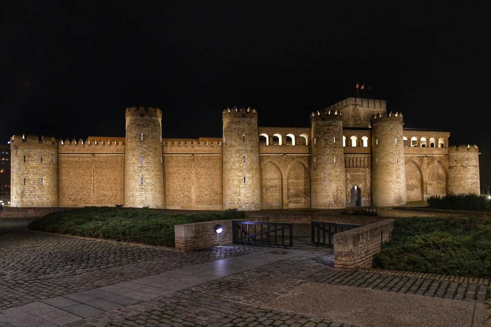 "castello di saragozza di notte illuminato con quattro grandi bastioni"