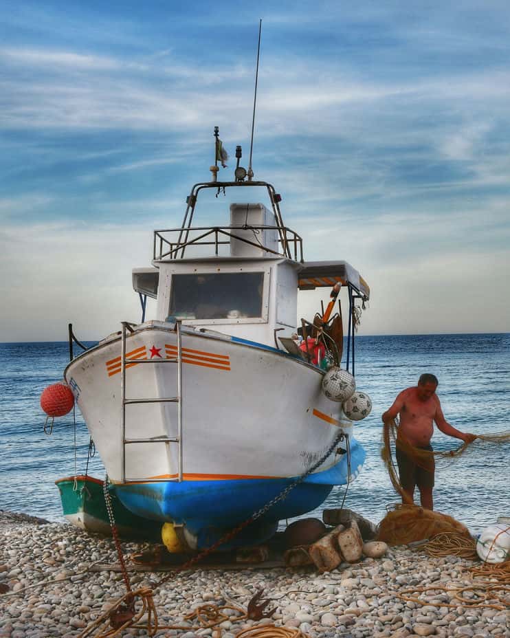 "pescatore sistema le reti da pesca vicino alla sua barca"
