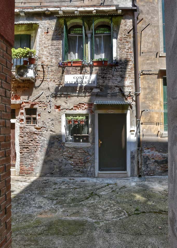 "piccola corte con porta e poggiolo fiorito vista verticale"