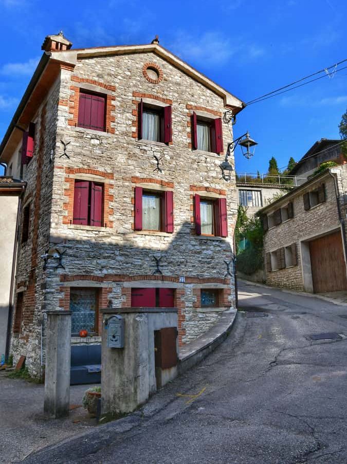 "casa in pietra tre piani con grandi finestre in legno marrone"