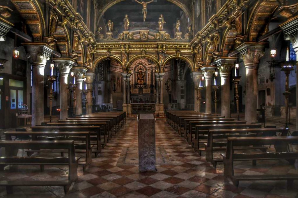 "interno chiesa decorato in oro con panche e luci soffuse"